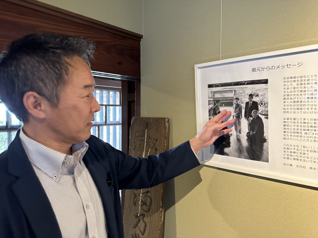 모리노쿠라 양조장의 모리나가 가즈히로 대표(5대)가 선대 대표·도우지(총책임자)들이 함께한 사진을 가리키며 옛이야기를 들려주고 있다.