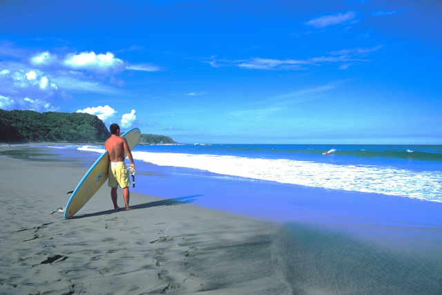 한 남성이 가네하마 해변에서 서핑을 즐길 준비를 하고 있다. 가고시마현 관광연맹 제공